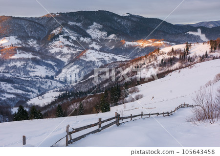 carpathian rural landscape i winter. wooden fence on the snow covered hill. bright sunny day carpathian rural landscape i winter. wooden fence on the snow covered hill. bright sunny day 105643458