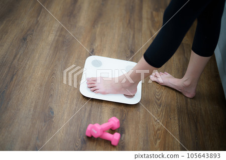 Fat diet and scale feet standing on electronic scales for weight control. Measurement instrument in kilogram for a diet control 105643893