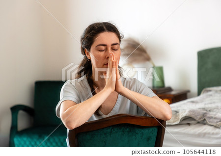 Portrait of sad young woman pray sitting on armchair. Concept of depression, psychology and mental problems Portrait of sad young woman pray sitting on armchair. Concept of depression, psychology and mental problems 105644118