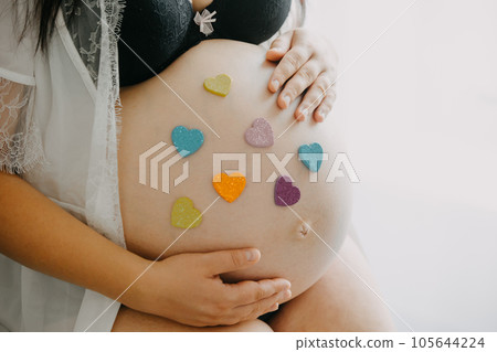 Young pregnant woman with belly and two heart stickers, pink and blue, pregnancy concept 105644224