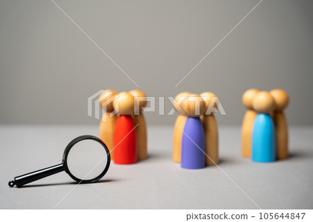 The concept of market segmentation. Target audience, customer care. Market group of buyers. Customer relationship management. Wooden figurines of people and magnifying glass 105644847