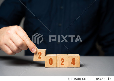 Businessman holding wooden blocks 2024. Business plan and strategy concept. Planning. Targets and goals. Financial plans, performance 105644912