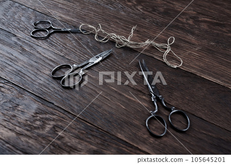 Antique old vintage retro scissors with thread on wooden table. Antique old vintage retro scissors with thread on wooden table. 105645201