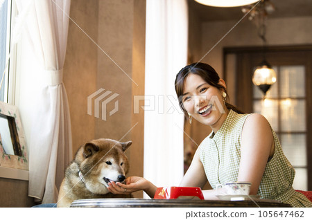 Young woman feeding her dog at a dock cafe Young woman feeding her dog at a dock cafe 105647462