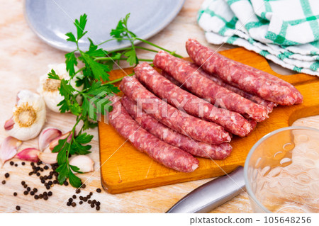 Raw pork longaniza ready for grilling on wooden board with condiments 105648256