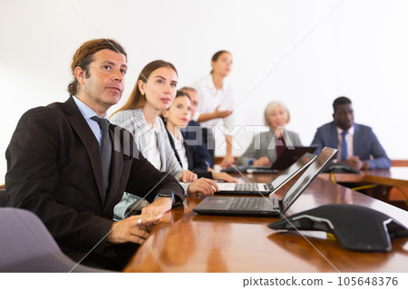 Middle aged white brunette businessman listening to presentation 105648376
