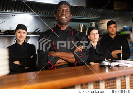 Team of confident chefs look at camera on kitchen restaurant Team of confident chefs look at camera on kitchen restaurant 105648438