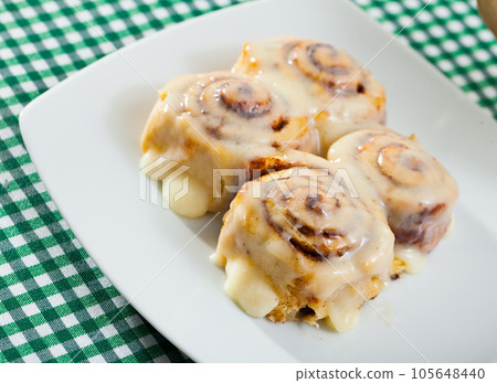 Rolled cinnamon buns on white plate Rolled cinnamon buns on white plate 105648440