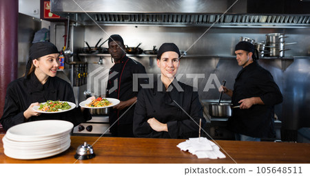 Woman head chef posing in restaurant kitchen Woman head chef posing in restaurant kitchen 105648511