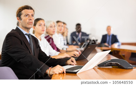 Man in suit attending meeting and using laptop 105648550