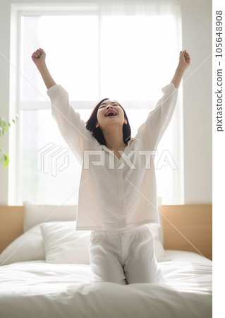一位女士在家裡明亮的臥室裡醒來，清新的早晨陽光透過窗戶照射進來“人工智能生成的圖像” 105648908
