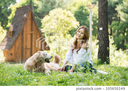 a happy young woman taking a walk with her dog in the park 105650149