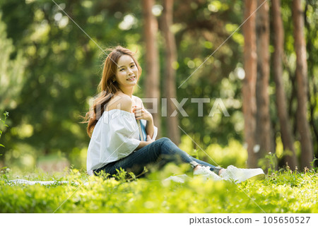 a beautiful young woman reading a book in the park 105650527