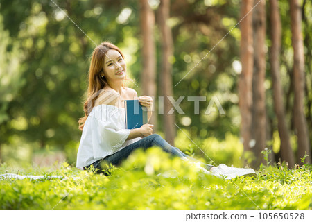 a beautiful young woman reading a book in the park a beautiful young woman reading a book in the park 105650528