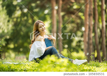 a beautiful young woman reading a book in the park 105650531