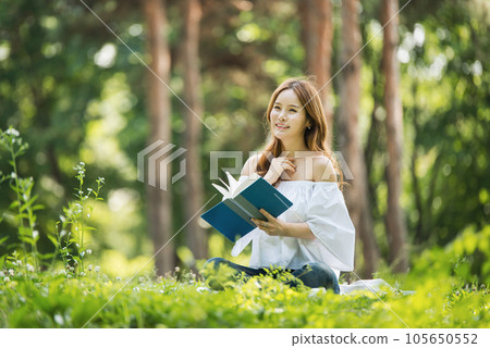 a beautiful young woman reading a book in the park 105650552