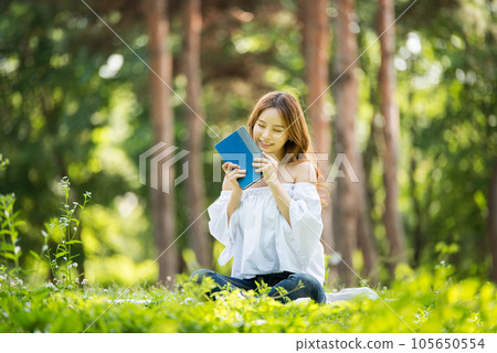 a beautiful young woman reading a book in the park a beautiful young woman reading a book in the park 105650554