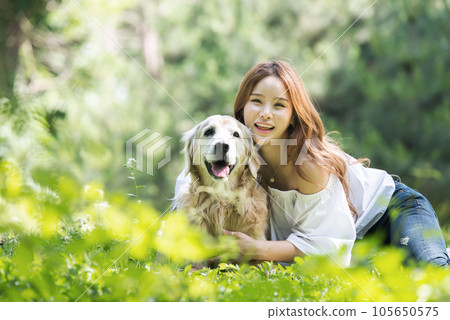 a happy young woman taking a walk with her dog in the park 105650575