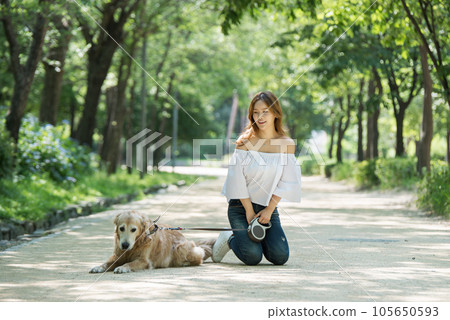 a happy young woman taking a walk with her dog in the park a happy young woman taking a walk with her dog in the park 105650593