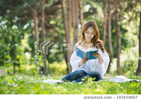 a beautiful young woman reading a book in the park 105650607