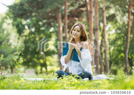 a beautiful young woman reading a book in the park a beautiful young woman reading a book in the park 105650610