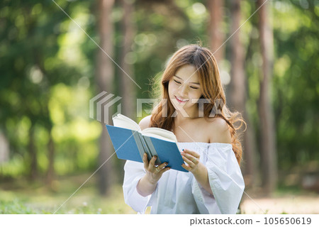 a beautiful young woman reading a book in the park a beautiful young woman reading a book in the park 105650619