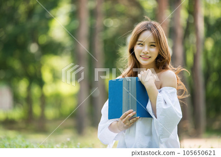 a beautiful young woman reading a book in the park a beautiful young woman reading a book in the park 105650621