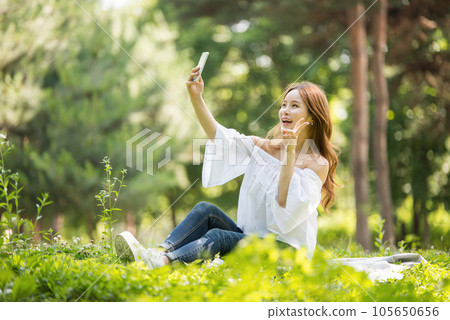 A beautiful young woman looking at her smartphone in the park A beautiful young woman looking at her smartphone in the park 105650656