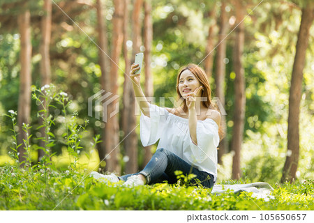 A beautiful young woman looking at her smartphone in the park 105650657