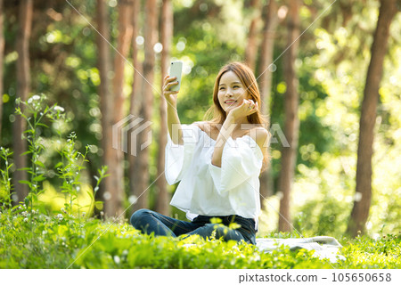 A beautiful young woman looking at her smartphone in the park A beautiful young woman looking at her smartphone in the park 105650658