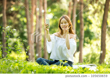 A beautiful young woman looking at her smartphone in the park A beautiful young woman looking at her smartphone in the park 105650659