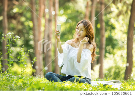 A beautiful young woman looking at her smartphone in the park A beautiful young woman looking at her smartphone in the park 105650661