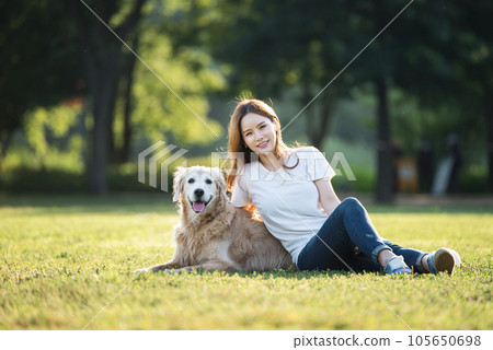 a happy young woman taking a walk with her dog in the park a happy young woman taking a walk with her dog in the park 105650698