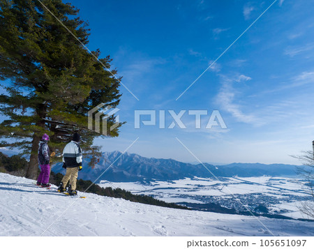 Snowboarders overlooking the snow-covered townscape from the ski resort (Inawashiro Ski Resort, Fukushima Prefecture) 105651097