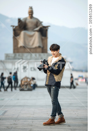 A young man holding a camera and taking pictures during a trip to Korea A young man holding a camera and taking pictures during a trip to Korea 105651269