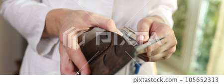 Woman doctor puts money in purse. 105652313