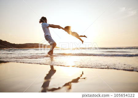 Father, spin girl kid and beach with games, holding hands or sunset for bonding together by waves. Dad, female kid and swing for love, care or play by sea, silhouette or family on vacation in summer 105654122