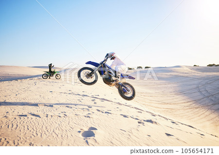 Motorcycle, desert race and jump in air for competition, stunt and outdoor for performance, goal and speed. Motorbike athlete, dunes and ramp in nature, sand and together for training in mockup space 105654171