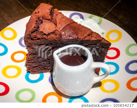 Chocolate brownies cake with chocolate sauce on top and whip cream on colorful dish Chocolate brownies cake with chocolate sauce on top and whip cream on colorful dish 105654217