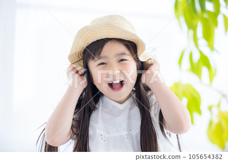 Portrait of a girl A girl holds her straw hat so that it won't blow away in the wind 105654382