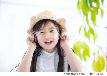 Portrait of a girl A girl holds her straw hat so that it won't blow away in the wind 105654402