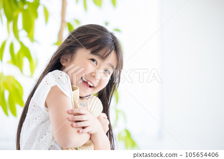 Portrait of a girl A girl holds her straw hat so that it won't blow away in the wind 105654406