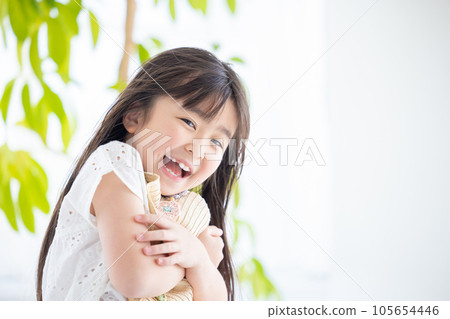 Portrait of a girl A girl holds her straw hat so that it won't blow away in the wind 105654446