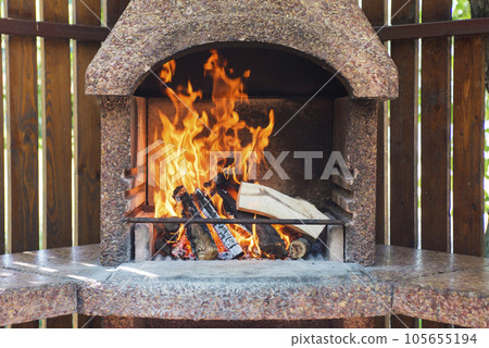 Stationary barbecue fireplace with burning wood at summer day. 105655194