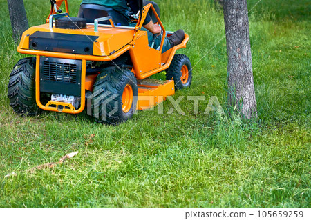 Professional grass cutting on lawns with a mini tractor lawn mower. Professional grass cutting on lawns with a mini tractor lawn mower. 105659259