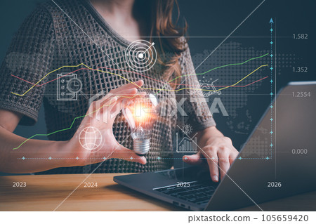 Businesswoman holding light bulb with computer laptop and stock market or forex trading graph. Candlestick chart suitable for financial investment money. Goal acheiveement and success concept. 105659420