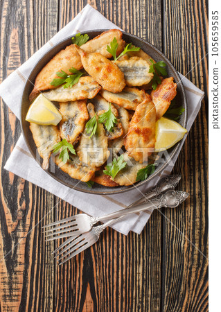 Healthy Mediterranean or Greek appetizer of fried anchovies in batter closeup. Vertical top view Healthy Mediterranean or Greek appetizer of fried anchovies in batter closeup. Vertical top view 105659585