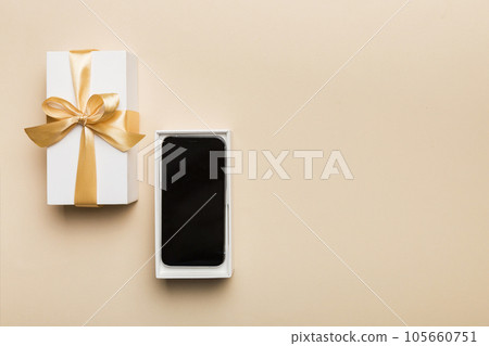 Opened gift box with gold ribbon and smartphone on color background, top view. Blank open box packaging mockup , Template for your design - branding mockup 105660751