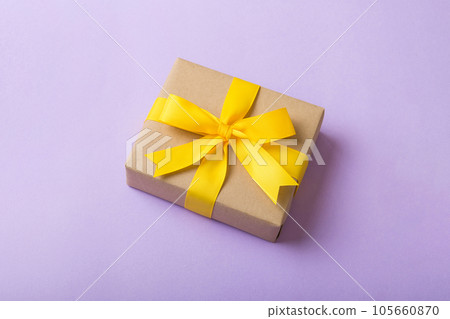 Wrapped christmas or other holiday handmade present in craft paper with colored ribbon. Present box, decoration of gift on table, top view with copy space 105660870