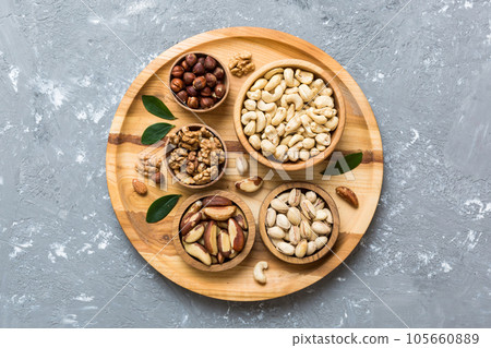 mixed nuts in wooden bowl. Mix of various nuts on colored background. pistachios, cashews, walnuts, hazelnuts, peanuts and brazil nuts 105660889